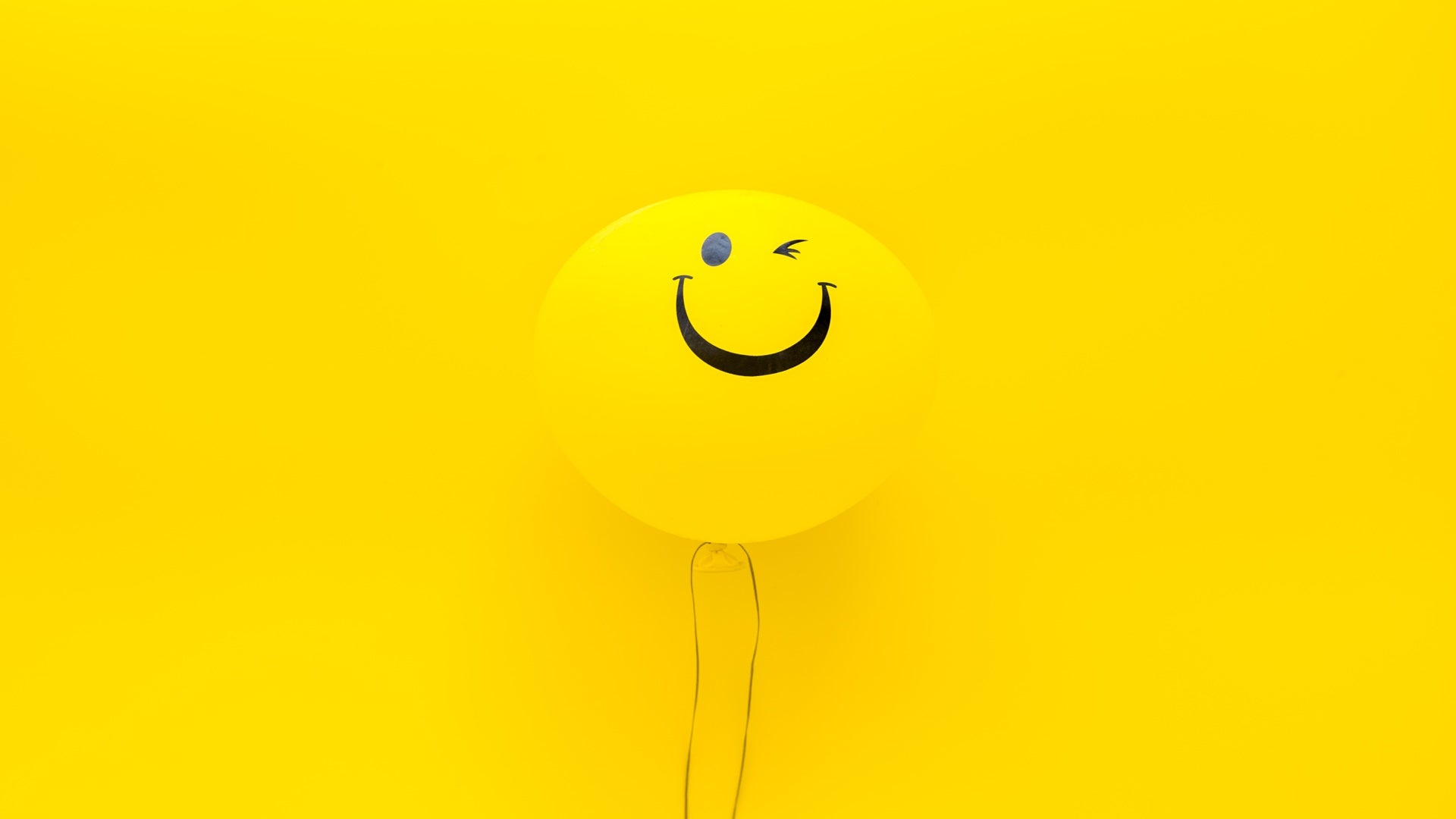 Happiness emotion. Yellow balloon with smile on yellow background top view.